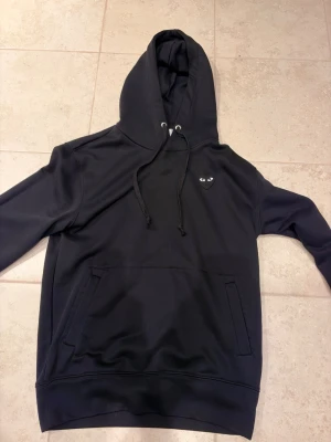 Comme des Garçons  - Comme des Garçons PLAY. Storlek S . Fraktar samma dag! OBS fläcken på tröjan där uppe är vatten !