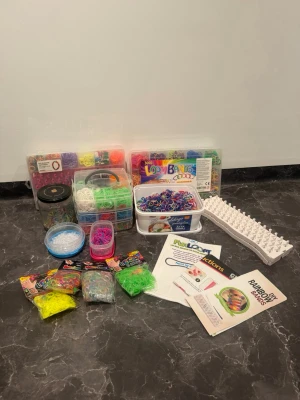 Stort set med färgglada loom bands - Säljer ett stort set med massor av färgglada loom bands i olika nyanser. Perfekt för att göra egna armband och smycken. Inkluderar flera askar med gummiband, verktyg, instruktioner och tillbehör. Materialet är elastiska gummiband i regnbågens alla färger.