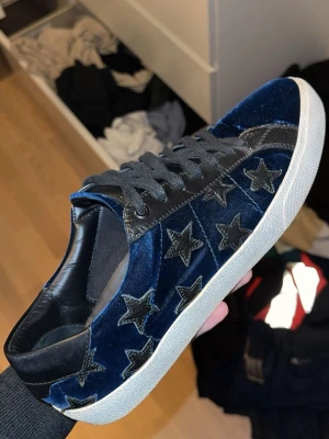Blå sneakers med stjärnor - Ett par unika mörkblå Yves saint Laurent skor i storlek 42✅ Skorna är i bra skick men har lite små skavanker och har släppt lite i sulan till höger om vänster skon. (Inget som inte går att fixa) Nypris: ca 7000 - 9000kr, Mitt pris: 2499kr🔥