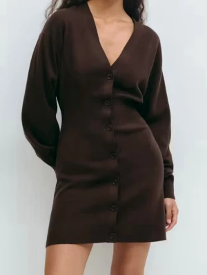 Ny Gina Tricot stickad kortklänning med knappar - Mörkbrun stickad klänning med v-ringning och långa ärmar. Klänningen har en rad knappar framtill och en figurnära passform som ger en snygg siluett. Perfekt för dig som gillar stilrena och enkla plagg.