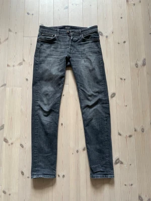 Svarta jeans - Jack & Jones  - Svarta jeans från Jack & Jones, modell Tapered / Mike. I bra skick med endast en liten defekt vid vänster fickan (se bild 5), en liten orange fläck. Bra passform och lätt att stylea.                  Storlek: 30 34 