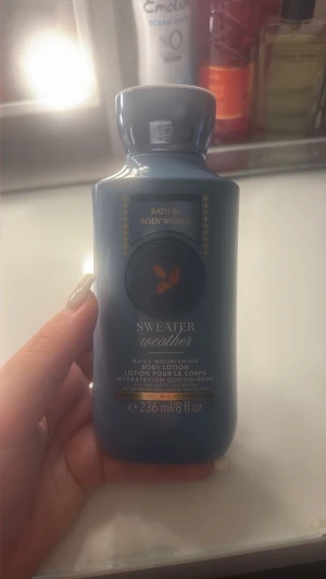 Bath body works Sweater Weather body lotion blå - En blå flaska med Bath & Body Works Sweater Weather daily nourishing body lotion. Innehåller 236 ml och har en elegant, rundad form med gulddetaljer på etiketten. Perfekt för dig som vill ha en återfuktande lotion med fräsch doft.