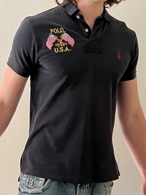Ralph Lauren Piké - Äkta vintage i använt skick. Slitage finns, flera små hål vid båda armhålor. Storlek custom fit M. För liten för mig (180cm, se bild). Skicka ett meddelande om du har frågor eller vill se fler bilder, fick inte plats med alla bilder på lappar och slitage båda sidor.
