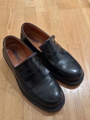 Loafers - Stilrena svarta loafers från Samsøe Samsøe i blankt läder. Sitter perfekt på min fot som ofta bär 42-43 i skor och dem är endast använda 2 gånger så en tvätt och då är dem så gott som nya, köptes i butiken i Stockholm för en bra bit över 2000kr så detta är ett kap!