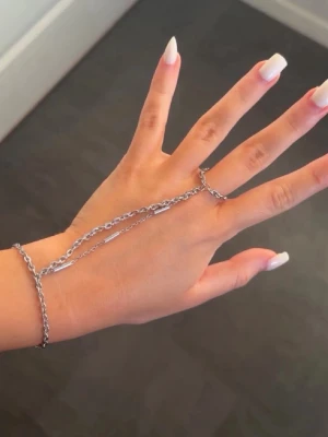 silver-handkedja  - Specialgjord silver-handkedja i indisk stil från By Sofia Wistam ✨ Unikt kvalitetssmycke gjort efter mina mått i butik. Vattenresistent och perfekt för vardagsbruk – jag har använt den med vatten, krämer, oljor och brun utan sol utan att den har rostat eller tappat färg. Nypris 2995 SEK. Passar handled ca 15-16 cm (min är 16 cm). Kedjan runt långfingret passar ungefär ringstorlek 5–7. Säljes endast eftersom jag använder ett annat smycke mer just nu. Priset kan diskuteras 🤍 
