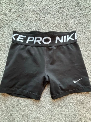 Svarta Nike Pro träningsshorts - Säljer ett par svarta Nike PRO shorts som har varit i fint skick. Ett par träningsshorts som jag säljer pågrund av att de är försmå för mig. De är i storlek M i junior size. Så ungefär 146 i barnstorlek. 