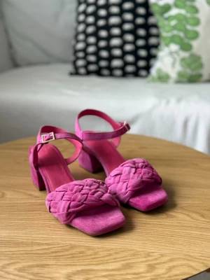 Flätade rosa sandaler med klack Copenhagenshoes 37 - Säljer ett par trendiga sandaler i rosa mocka med bred flätad rem över foten och justerbart ankelband med spänne. Sandalerna har fyrkantig tå och stabil blockklack som ger en cool vibe till din outfit. Säljes pga att de ej passar min fot. Nypris var 1195kr. Endast provade inomhus! 