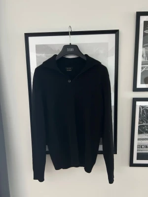 Svart tröja med krage Massimo Dutti - Säljer en svart långärmad tröja från Massimo Dutti med krage och två knappar framtill. Tröjan har en enkel och stilren design, perfekt för dig som gillar klassiska plagg. Materialet ser ut att vara mjukt och bekvämt S-M