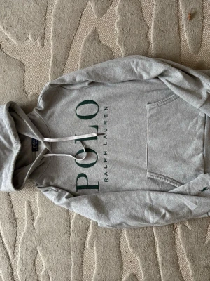 Grå hoodie Polo Ralph Lauren - Grå Ralph lauren hoodie med grön text. Storlek S. Mycket fint skick. 