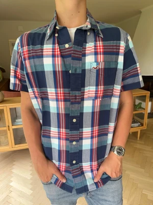 Hollister kortärmad skjorta herr rutig vintage - Snygg kortärmad rutig skjorta från Hollister. Härliga färger i blått, rött och vitt. Perfekt för sommaren eller lager-på-lager. Storlek M. I jättefint skick.#hollister #skjorta #rutig #kortärmad #sommar #herrskjorta #M #plaid. Passar dig som är 176-190cm
