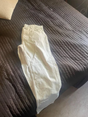Vita raka jeans från Junkyard - Säljer ett par vita jeans från Junkyard med rak passform och klassisk femficksdesign. Jeansen är tillverkade i ett kraftigare bomullstyg och har en stilren look som passar till det mesta. Perfekta för dig som gillar en clean och enkel stil.