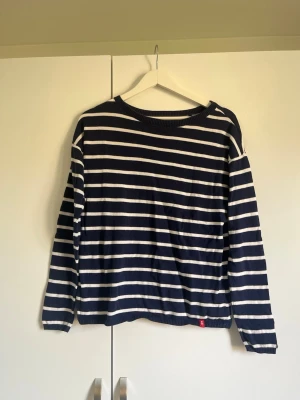 Marinblåvit randig stickad tröja EDC - Säljer en marinblå stickad tröja från EDC by Esprit med vita horisontella ränder. Tröjan har rund halsringning, långa ärmar och ribbade muddar. Perfekt för en avslappnad och stilren look. Materialet är mjukt och bekvämt.
