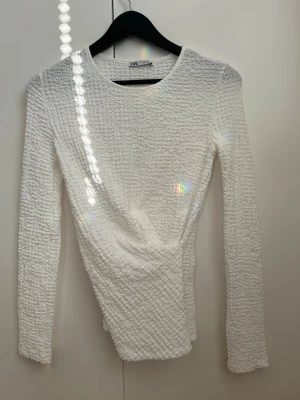 Vit ribbad långärmad topp från Zara - Säljer en vit långärmad topp från Zara med ribbad struktur. Toppen har en kroppsnära passform och rund halsringning. 