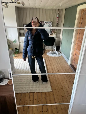Expedition jacka lite från Fjällräven - Snygg mörkblå dunjacka från Fjällräven med huva och gulddetaljer på dragkedjorna. Jackan har två stora framfickor med knappar, bröstficka och klassisk Fjällräven-logga på bröstet. Perfekt för kalla vinterdagar och riktigt varm. Den har aldrig kommit till användning så helt ny! Prislappen samt påse medföljer! Vid frågor får du gärna höra av dig🩷🩷
