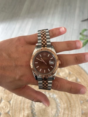 Rolx - En fin klocka för dig som behöver något på din arm. Den brun silvriga färgen är perfekt, elegant och stilig.