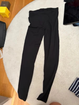 Svarta leggings från 157 - Svarta leggings från 157 i mjukt och stretchigt material. Tillverkade av 95% bomull och 5% elastan för en skön passform. Hög midja och klassisk, enkel design som funkar till allt. Perfekta för dig som gillar bekväma och stilrena plagg.