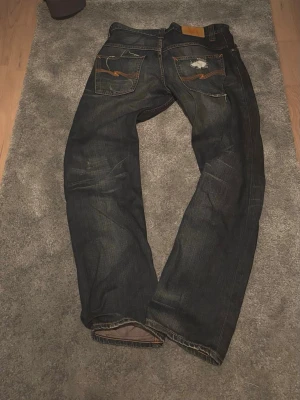 Slitna repaired Nudie jeans - OBS! SER MÖRKARE UT I LJUSET ÄN VAD DEM ÄR  Säljer dessa slitna Nudie jeans med as schyssta lagningar både fram och bak. Modellen är Even Steven så dem har en rak passform. Storleken på byxorna är 31/32 som du kan se. Hör av dig vid frågor.