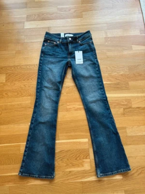 Blå bootcut jeans - Snygga blå bootcut jeans med klassisk femficksdesign och lätt slitna detaljer. Jeansen har normal midja och vida ben från knät och ner. Tillverkade i denim med en autentisk tvätt. Perfekta för en avslappnad och trendig look. Helt nya nypris; 599kr