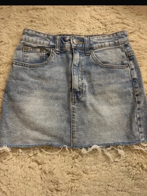 Jeanskjol - Lågmidjad jeanskjol med slitningar nertill, från PULL&BEAR i storlek 32! 