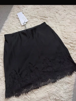 Spets kjol - Kort kjol i satin med spets nertill från Gina tricot i storlek 34! Ny med prislapp 
