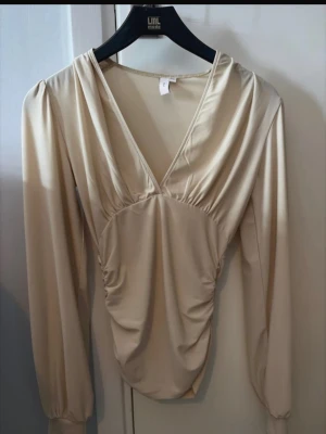 Tight topp - Beige topp som är figursydd i midjan och puffiga armar från Nelly! 