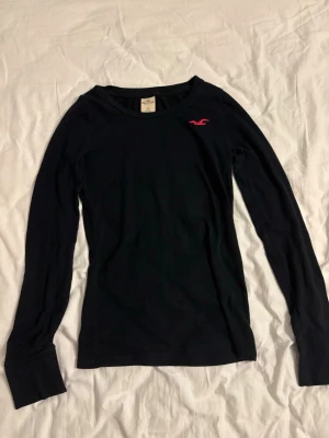 Hollister tröja - Säljer denna snygga långärmade tröjan från Hollister! Svart med en rosa logga. Köpt här på plick och endast använd fåtal gånger av mig. Har ett litet hål på undersidan av högra ärmen (se bild 4) Storlek M men sitter mer som en S. 