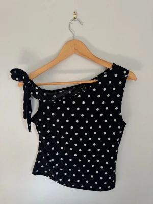 Prickig topp - Snygg svart oneshoulder topp med vita prickar och en knyt-detalj på axeln 💝