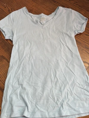 Ljusblå v-ringad t-shirt - En enkel och fräsch ljusblå t-shirt med v-ringning och korta ärmar.  Perfekt basplagg till garderoben och lätt att matcha med allt.