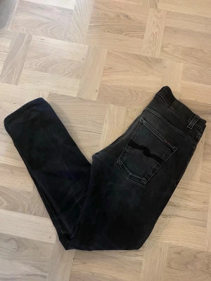 Svarta nudie jeans - Säljer ett par svarta Grim Tim Nudie jeans | storlek W32 & L32 men dom har krympt i tvätt så skulle säga W30 & L28 | På bilden är jag 179 cm och dom är för korta för mig | Tyvärr har höger framficka ett hål medans vänster har ett litet men funkar fortfarande | 