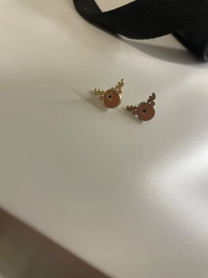 Guldiga renörhängen med bruna detaljer - Säljer ett par söta örhängen i form av renar med guldiga horn och bruna ansikten. Perfekta för dig som vill ha något lekfullt och unikt till öronen. Passar extra bra till vintern och julens alla tillfällen.