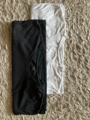 Svart och vit t-shirt från Gant - Två klassiska t-shirts från Gant i svart och vitt. Båda har rund halsringning och diskret logga på bröstet. Tillverkade i mjuk bomull och har en normal passform med korta ärmar. Perfekta basplagg till garderoben.