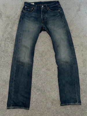 Levi jeans W29/L32 - Ett par klassiska Levi’s jeans med raka ben skön wash. Jeansen har fem fickor, knappgylf och kontrastsömmar. Materialet är robust denim i bomull och passformen är avslappnad men ändå stilren.