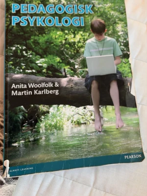 Psykologi kursbok av Woolfolk & Karlberg - Kurslitteratur i psykologi skriven av Anita Woolfolk och Martin Karlberg. Omslaget visar en person med laptop i naturmiljö. Perfekt för dig som pluggar psykologi på universitet eller högskola.