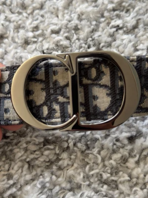 Sprillans nytt Dior bälte  - Dior bälte, klassiskt monogram med silvrigt CD buckle. Helt nytt med låda etc. Säljer pga för stor. Storlek 110. Diskuterar priset vid snabb affär eftersom att jag flyttar och behöver bli av med det.