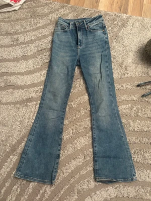 Blå Peachy Flare jeans XS - Säljer ett par blå Peachy Flare jeans i storlek XS med längd 31. Jeansen har hög midja, klassisk femficksdesign och utsvängda ben. Materialet är klassisk denim i bomull.