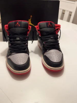 Air Jordan 1 Mid svart/röd/grå - Säljer ett par Air Jordan 1 Mid i svart/röd/grå. Storlek 44. Skorna är i bra skick och har använts sparsamt. Inga större defekter. Snygg klassisk Jordan-modell som passar både till vardags och streetwear. Hör gärna av dig vid frågor!