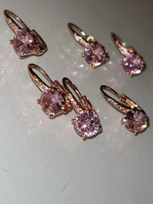 Rosa gnistrande örhängen i guldton - Säljer 6 stycken örhängen i guldton med stora, runda rosa stenar som gnistrar snyggt i ljuset. Klassisk krokstängning och elegant design som verkligen sticker ut. Perfekta för dig som vill ha något glammigt och trendigt i smyckeskrinet.