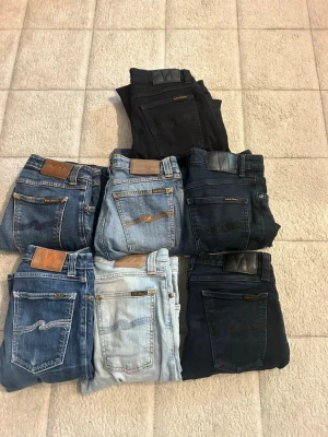 Mix av Nudie Jeans i olika tvättar - Säljer ett gäng Nudie Jeans i olika blå och svarta tvättar. Klassisk femficksmodell med kontrastsömmar och läderpatch bak. Finns både ljusa, mellanblå, mörkblå och svarta jeans. Perfekta för dig som gillar stilrena och tidlösa jeans.