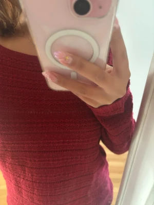 Mörkröd långärmad tröja - En mörkröd långärmad tröja med diskret strukturmönster. Tröjan har en rund halsringning och är figurnära i modellen. Perfekt för dig som gillar en enkel men snygg stil. Underbar till hösten 