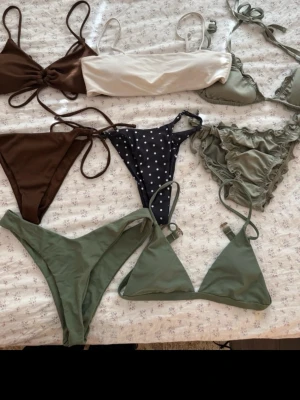 Mix av bikinis i grönt, brunt och svart - Säljer ett paket med flera bikinis i olika stilar och färger: olivgrön, brun, vit och svart med vita prickar. Några har volangdetaljer och snörning, andra är enkla med trekantsformade kupor. Perfekt för dig som vill variera strandlooken! Storlek xs-s men alla passar både xs/s. Ifrån Kappahl och shein!