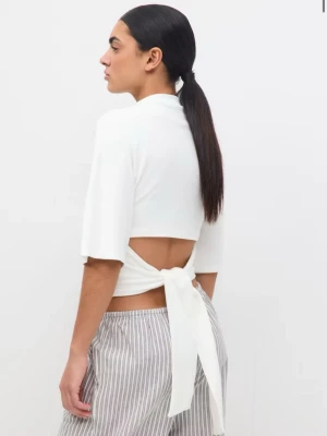 Tie back tee -  Croppad t-shirt med knytdetalj i ryggen. T-shirten är vit och har kort ärm. Den har hög halsringning och normal passform. Använd vid ett tillfälle