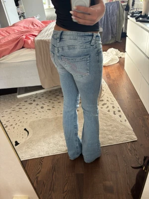 Ljusblå bootcut jeans med broderad ficka - Säljer ett par ljusblå bootcut jeans med låg midja och snygg broderad detalj på bakfickan. Knappt använda.