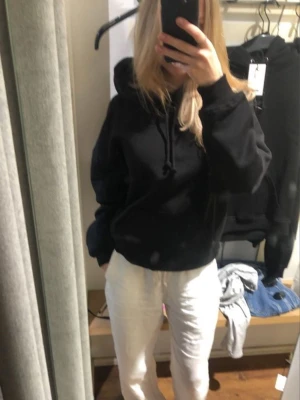 Svart hoodie med huva - Säljer en klassisk svart hoodie med huva och dragsko. Hoodien har en avslappnad passform och är perfekt för en chill look. Tillverkad i mjukt material som känns skönt mot huden. Passar till det mesta och är enkel att styla.