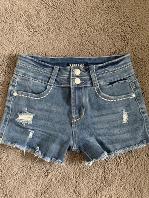Jeans shorts  - Blå jeansshorts, midwaist, dubbla knappar och dekorativa sömmar/stenar. Står storlek ”1” - skulle uppskatta dem att passa som eu 36/38. Bekväma och väldigt stretchiga.
