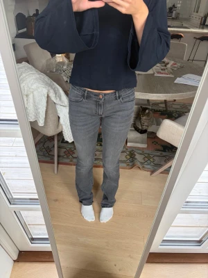 Grå wrangler jeans med låg midja - Säljer ett par grå jeans, bootcut och låg midja. Jeansen har klassisk femficksdesign och stängs med knapp och dragkedja. Materialet känns mjukt och följsamt.