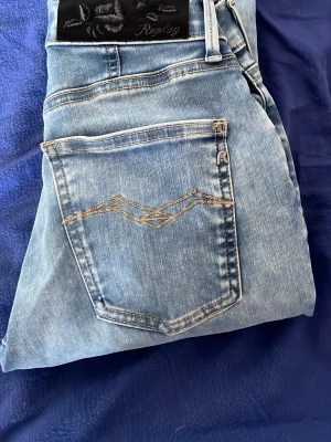 Ljusblå jeans från Replay - Säljer ett par ljusblå jeans från Replay med klassisk femficksmodell och snygga kontrastsömmar på bakfickan. Jeansen har normal midja och raka ben. Materialet är mjukt denim som ger en avslappnad look.