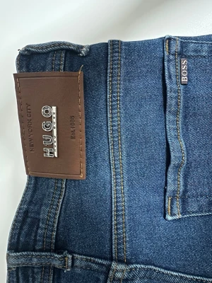 Mörkblå jeans från Hugo Boss - Snygga mörkblå jeans från Hugo Boss med klassisk femficksmodell och raka.                                Längd 100 cm                                                                    Midjemått 85 cm 