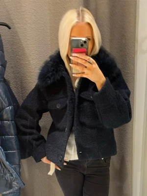 Mörkblå jacka med fuskpäls - Mysig mörkblå jacka med fluffig fuskpäls runt kragen. Köpt från Gina, endast använd nån gång.