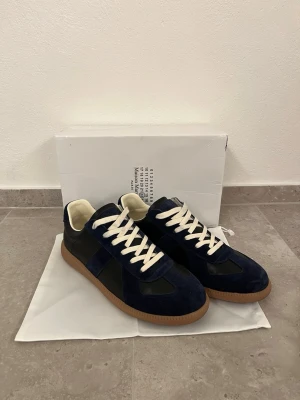 Mörkblå gats med mockadetaljer - Snygga sneakers i mörkblå mocka och svart läder med vita skosnören och beige innersula. Yttersulan är i gummi med klassisk brun färg. Skorna har en stilren och tidlös design som passar perfekt till jeans eller streetwear. Snygga gats, maison margiela#grisch #2000s #y2k #archive #niche #2016s #fakemink #feng #youngthug #stockholm #ungdom #snygg #marinblå #svart #vit #fin #unik #123 #456 #789 #archivedesigner #timelessdesign #vintage #vinted #fashion #collectorsitem #vintagedesigner #mönster #man 