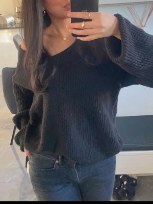 Svart stickad tröja från NAKD - Mysig svart stickad tröja med v-ringning och avslappnad, oversized passform. Tröjan har långa ärmar och en lätt off-shoulder look. Perfekt för dig som gillar en chill och trendig stil. Man kan även ha tröjan på andra hållet så den får en djup rygg istället. Storlek xxs men lite stor i storleken. Superbra skick! 
